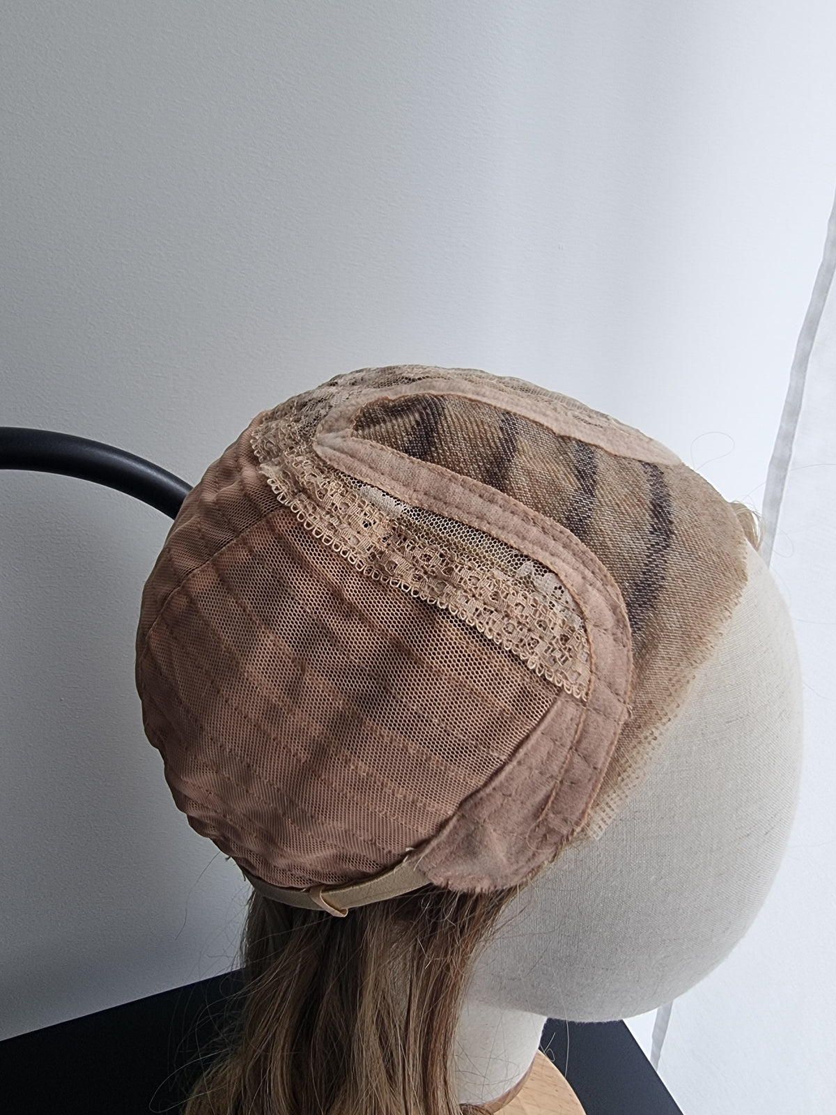 A  wig cap with a fine mesh texture monofilament, displayed on a mannequin head with light brown hair.
