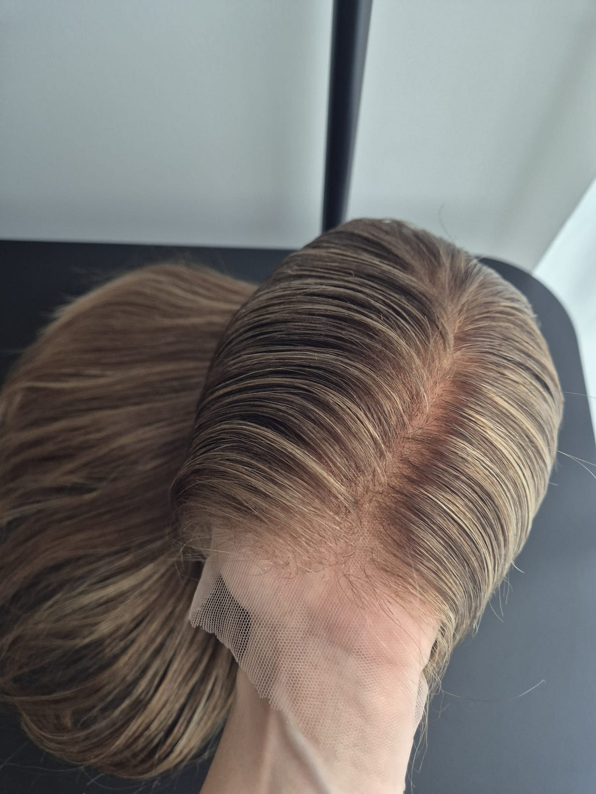 Closeup  of the hair parting of a human hair wig with bleached knots held against the skin of a human hand