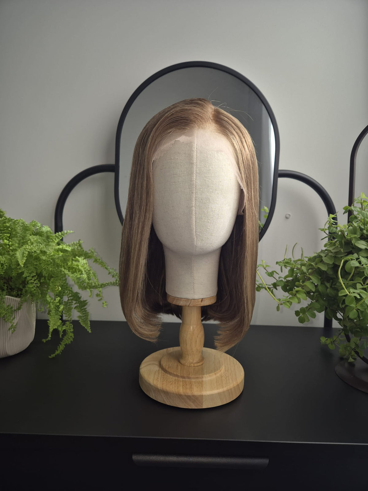 A shoulder-length straight wig with side parting in light brown and blonde tones, displayed on a fabric mannequin head.