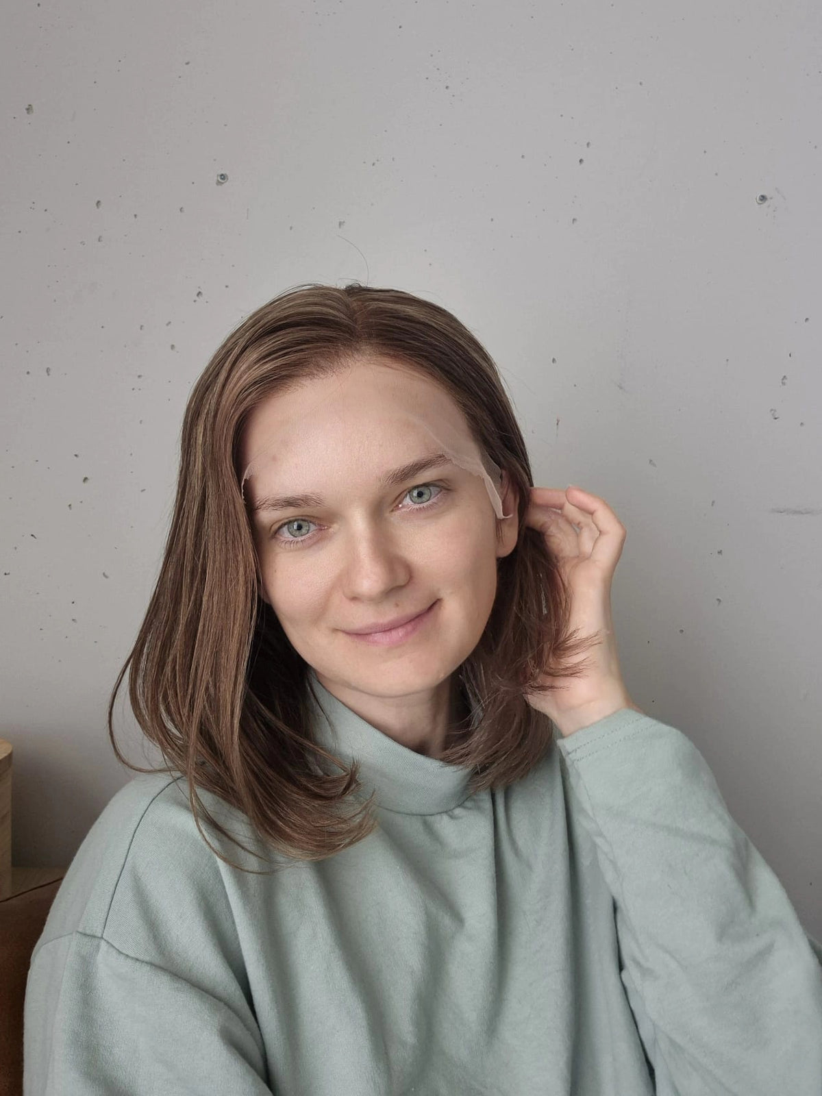 A woman wearing a shoulder-length light brown hair human hair wig